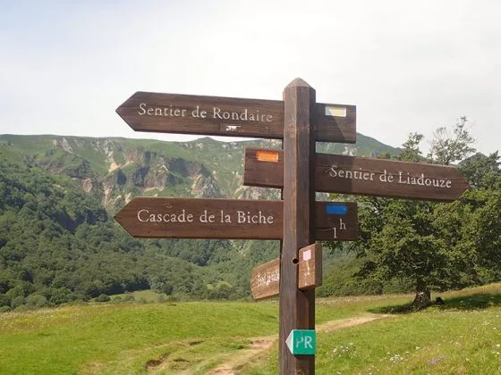 Panneau indiquant les directions de plusieurs randonnées en Auvergne