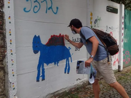 Cédric imite la réalisation d'un street art sur les murs de Gand avec une œuvre représentant une créature enfantine